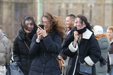 Tourists walking on Westminster Bridge in central London brave strong winds caused by Storm Isha.