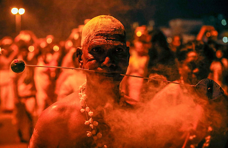 A Hindu devotee with his face pierced with a metal rod takes part during the Thaipusam festival at the Batu Caves on the outskirts of Kuala Lumpur. Thaipusam is a Tamil Hindu festival celebrated on the full moon day of the Thai month. It marks the victory of the Hindu god Murugan over the demon Surapadman with a divine spear from Parvati. The festival involves Kavadi Aattam, a ceremonial sacrifice carrying a physical burden, and rituals like carrying a pot of cow milk as an offering. Devotees prepare by maintaining cleanliness, regular prayers, a vegetarian diet, and fasting.