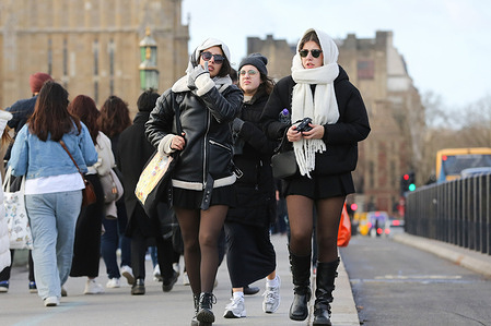 Tourists walk on Westminster Bridge in London on a windy day in the capital.