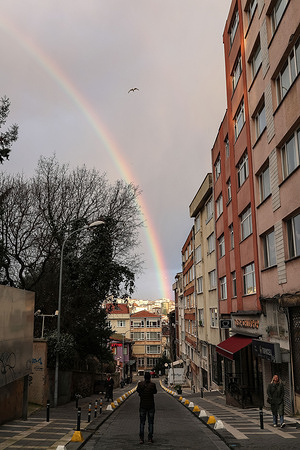 A man takes a photo of a rainbow that appears in the sky in Istanbul.