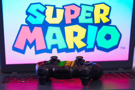 In this photo illustration, the Super Mario logo game is displayed on a computer screen, next to a gamepad.