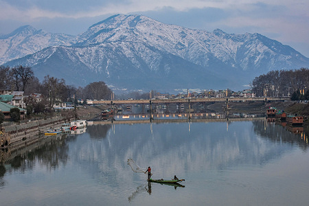 A fisherman casts his net into river Jhelum during a cold winter day in Srinagar. Weather across the Kashmir valley has improved after receiving fresh snowfall following prolonged dry weather. The flight operations at Srinagar Airport and road traffic on the Srinagar-Jammu highway that were hit by the snowfall on Sunday were restored on Monday.
