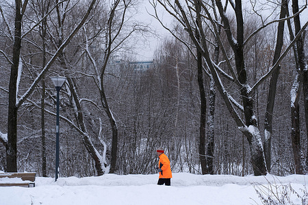A man in an orange jacket goes jogging in a winter park in Moscow