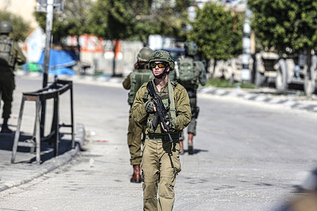 An Israeli soldier stands on guard near the site where an Israeli soldier shot a Palestinian youth at Israeli Deir Sharaf checkpoint. Palestinian Red Crescent ambulance personnel reported that the soldier who shot a young man prevented them from treating him and left him to bleed to death.