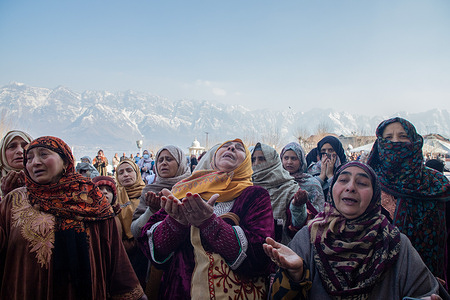 Muslim women raise their hands in prayers as the head cleric (unseen) displays the holy relic believed to be a hair from the beard of Prophet Muhammad (PBUH) on the occasion of Lailat-al-Meraj or Shab-e-Meraj at the Hazratbal shrine in Srinagar.