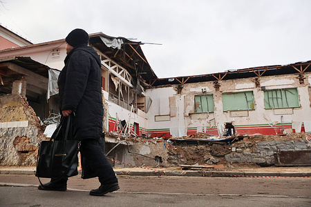 A woman walks past the damaged sports complex of the Lokomotyv Kyiv football club after a Russian missile strike on January 23, 2024.