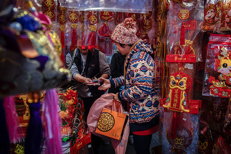 A woman purchases decoration items in a street market ahead of the Spring Festival, or the Chinese Lunar New Year. Flowers play a huge role in the celebration of Chinese New Year in Hong Kong and the days prior the New Year’s celebration represents the annual peak of sales for the industry.