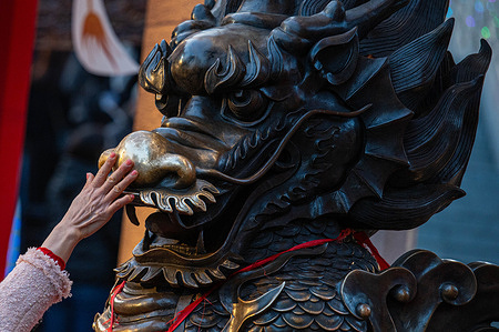 A woman touches a dragon statue for health and prosperity to kick off the Year of the Dragon at the Wong Tai Sin Temple. The Sik Sik Yuen Wong Tai Sin Temple is one of the largest Taoist temples in Hong Kong and many people come here to offer the first joss sticks of the new year along with prayers for happiness and health.