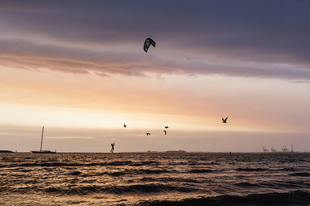After a day of wild weather and storms in Melbourne, a kiteboarder lifts in the air as the sun sets at St Kilda beach.