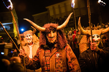 The Felos (carnival revellers of Maceda) wearing wooden masks and horns seen during the "Baixada da Marela" parade. After spending the day visiting neighboring villages, the Felos undergo a transformation, assuming demonic personas adorned with horns and animal skins. As dusk falls, they lead a parade through the streets of Maceda, located in Galicia, northern Spain, with a wooden cow. The procession is accompanied by fire, booming bass drums, frenetic rhythms, and copious amounts of flour fired in all directions, creating a scene of abundant enjoyment known as the "Baixada da Marela."