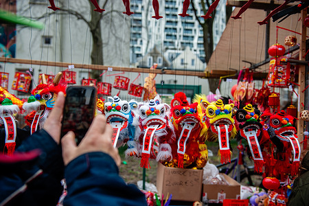 A man is taking a photo of little dragons in one of the market stalls. Lion dancers and dragon dancers parade through the streets of Rotterdam to bless the new year entrepreneurs. The lion dance ceremony ensures that evil spirits are chased away and brings prosperity and happiness for the new year. The Chinese communities in Rotterdam are celebrating a 15-day festival to mark the Chinese New Year for the Year of the Dragon, which began on January 21 and will continue until February 20 in the Western calendar. During this time, people are engaging in various festivities, including prayers, family feasts, and shopping sprees, to usher in the new year.