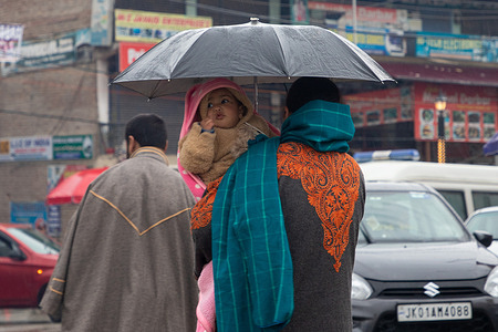 A Kashmiri woman carrying a child holds an umbrella during the rainfall on a cold winter day in Srinagar, the summer capital of Jammu and Kashmir.