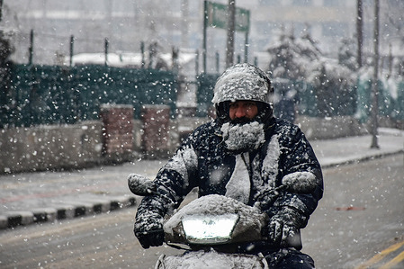 A man rides his scooter along the snow covered road during heavy snowfall in Srinagar.Srinagar city received snowfall on Tuesday as higher reaches of Kashmir have witnessed bountiful snowfall over the past 48 hours, officials said here.The National Highway remained closed and flight services to and from Srinagar were canceled.