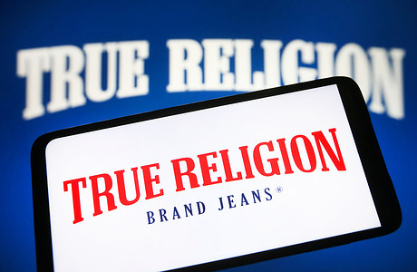 In this photo illustration, True Religion Brand Jeans logo is seen on a smartphone screen.