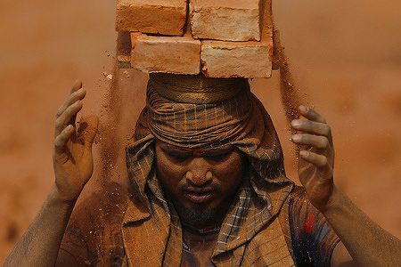 A worker stacks bricks on his head at a brick kiln in Bhaktapur. Nepali and Indian seasonal laborers arrive during the winter season to work at brick kilns for 3 months.