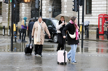 Members of the public walk during rainfall in Westminster in central London.
