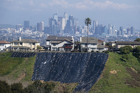 Residential homes near hill sides use tarps to safeguard against storm-induced property damage in Los Angeles, February 22, 2024.