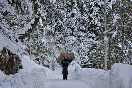 A man carries furniture on his head as he walks through the snow-covered road during a winter day in Drung, about 45kms from Srinagar, the summer capital of Jammu and Kashmir.
