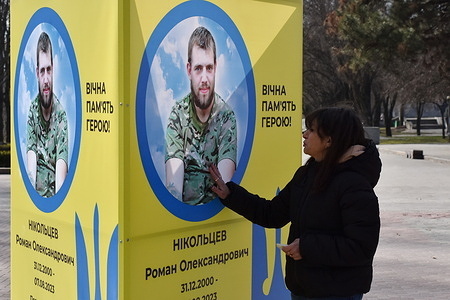A woman is seen next to the stand of portrait of fallen Ukrainian soldier in the center of Zaporizhzhia. Ukrainian President Volodymyr Zelensky has marked the second anniversary of Russia’s invasion by saying his country "will succeed." Ukraine defied predictions that it would not be able to resist Russia but there are signs of the war turning in Russia's favour. The Ukrainian government does not generally publicise the number of its military dead. But the ever-growing number of fresh graves, on both sides of the front lines, paints a painfully clear picture.