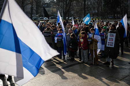 Protesters hold flags and anti-war placards during the demonstration. Russian protesters assemble for an anti-war rally organized by the Russian diaspora, rallying under the slogan "A World Without Putin." Demonstrators prominently display the white-blue-white flag, a symbol of opposition to the Russian invasion of Ukraine and widely adopted by Russian anti-war activists.