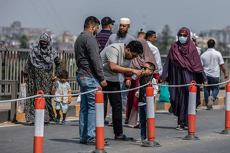 A child drinks water while crossing the Postogola Bridge with his family members. The first Buriganga Bridge in Dhaka known as Postogola Bridge closed for repairs until Mar 8, according to the Road Transport and Highways Division.