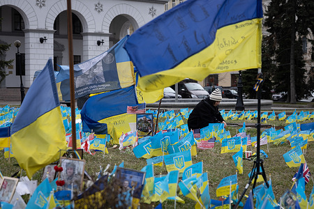 A woman places a flag on an improvised memorial site on Independence Square in Kyiv, where relatives and friends plant Ukrainian flags with the names of military personnel killed in battles with the Russian army. As Ukraine marks two years since the full-scale Russian invasion, a gloomy mood hangs over the country. On the battlefield, Ukrainian troops are running low on ammunition as they look for further Western help.