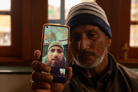 A father of Azad Yousuf Kumar, holds a smart phone displaying the photos of Azad Yousuf Kumar, wearing military uniform, at Pulwama village. Two Kashmiri men Azad Yousuf Kumar 31-years old, and Zahoor Ahmad Sheikh 30-years old, who were lured to Dubai on the promise of jobs and then deceitfully dispatched to Russia by fraudulent recruitment agencies and ordered to fight as mercenaries for Russia on the border with Ukraine. A Kashmiri family learned that their son, Azad Yousuf Kumar, 31- years old, had been injured in the Russia-Ukraine conflict. The family said the 31-years old was forced to fight in the war on frontline and urged the Indian government to intervene to help them get their son back. At least a dozen Indian nationals have been duped by the agents into fighting for Russian forces in the country's war with Ukraine. According to the Indian publication 'The Hindu', one Indian national was killed in a missile strike last week. The anguished families of the trapped men have now petitioned the federal government to return them home.