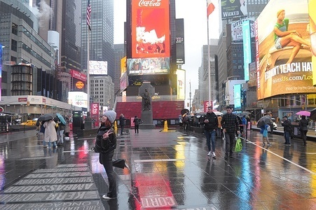 A pedestrian poses for a picture in Times Square, New York City on a rainy day.