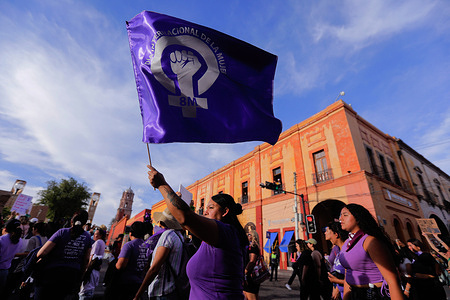 A woman waves a flag during the International Women's Day march. Women from Querétaro celebrated International Women's Day with a march that concluded in the Plaza de la Constitución, where they called for an end to violence and demanded respect for their rights.