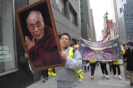 A pro-Tibet demonstrator marches holding a photo of the 14th Dalai Lama during the 65th Tibetan Uprising Day. Demonstrators rallied in Manhattan, New York City demanding Tibet's independence from China. The Tibetan Uprising Day marks the day in 1959 when thousands of Tibetans in Tibet surrounded the palace of the current and 14th Dalai Lama. The Dalai Lama is the spiritual Buddhist leader of Tibetans worldwide. The Tibetans surrounded the palace in 1959 to protect the Dalai Lama due to fears of a Chinese government plot to abduct him. On March 17, 1959, the Dalai Lama was forced to flee from Tibet to India to escape the threat of the Chinese government. Since 1959, the Dalai Lama has been living in exile in Dharamshala in northern India. The Chinese communist chairman, Mao Zedong, annexed Tibet in 1950 after a military invasion. Annually on Tibetan Uprising Day, demonstrators globally hold rallies demanding human rights and independence for Tibet, which has been under Chinese rule for more than 70 years.