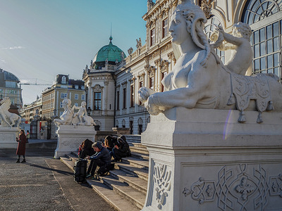 Tourists sit on the steps of the southern entrance of the Belvedere Museum. Belvedere Museum located in palaces owned by the Imperial family of the Austrian Empire. Now in the buildings of the Belvedere complex there is a famous art museum.