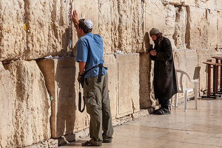 Jewish men pray by the Western Wall in the Old Town of Jerusalem. In Judaism tradition Western Wall is believed to be a remnant of the Holy Temple and the most sacred site of pilgrimage.
