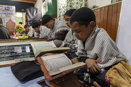 Kashmiri Muslim boy is seen reading from the Islamic holy book Quran in congregation during the holy fasting month of Ramadan in Srinagar.