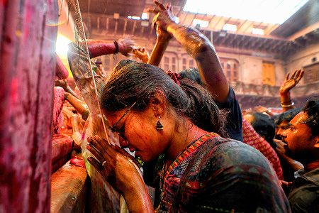 Hindu devotees offer prayers at the Radha Ballav Temple of Vrindavan. The Radha Ballav Temple is an important Hindu temple where Lord Krishna is worshipped, especially during the Holi Festival. This festival celebrates a legend about Krishna teasing his lover Radha, and it's celebrated at the Radha Rani temple in Barsana. During this time, men from Nandgaon visit Barsana, where women playfully hit them with sticks. The festival lasts for over a week and includes throwing colorful powders and liquids, as well as enjoying a traditional drink called Thandai.