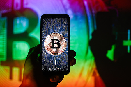 In this photo illustration a Bitcoin logo is displayed on a smartphone with Bitcoin logo on the background.