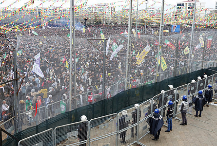 A 5-meter-high wire mesh and police barrier seen separating the celebration platform from the attendees at the Newroz celebration. The final day of the Newroz Holiday, which lasted for two weeks and was celebrated in 58 centers across Kurdish cities in Turkey, concluded with a massive rally and festival in Diyarbakir. Hundreds of thousands of people attended the event. Organized by Kurdish political parties and organizations such as the Peoples' Equality and Democracy Party (DEM Party), Democratic Regions Party (DBP), Democratic Society Congress (DTK), and Peoples' Democratic Congress (HDK), the celebration in Diyarbakir also saw participation from numerous leftist and socialist organizations.