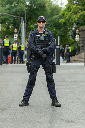 A riot cop tries to look menacing during an anti-trans protest and counter protest. The Victorian State Parliament steps witnessed a collision of ideologies as anti-trans demonstrators demand a platform while left-wing activists vehemently resist. Emotions soar amidst the charged atmosphere, with police presence intensifying to maintain order. Groups clashed as police tried to maintain order and the peace. Punches were thrown and a press photographer was knocked to the ground by police in the clashes.