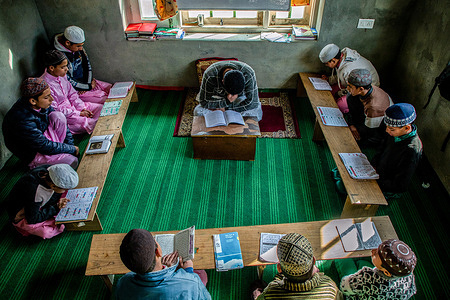 Muslim students read the Quran in front of their religious teacher at an Islamic school or madrasa in Srinagar.