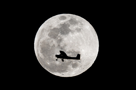 A plane flies past the full moon known as Worm Moon rising over Los Angeles.