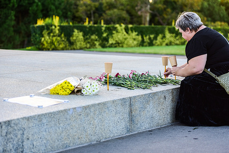 A woman lays flowers and lit candles at a makeshift memorial near the eternal flame at the Shrine of Remembrance in Melbourne to honor the victims of the terrorist attack at Crocus City Hall in Russia.