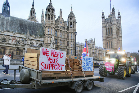 Tractors and trailers display placards as they drive past Parliament during the demonstration. Farmers gathered and rode into Parliament Square on over 130 tractors in a slow-moving protest, demonstrating against the insufficient support for British food production.