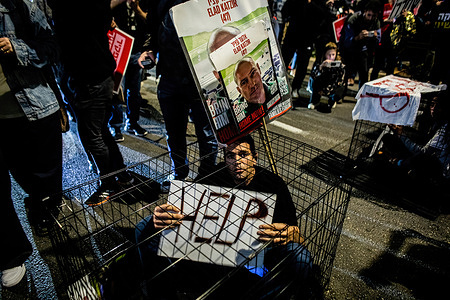 A protester sits in a cage during a protest urging the government to secure a hostage release deal with Hamas. Israel recalled its negotiating team from Qatar as Hamas rejected its latest offer. Negotiations, mediated by Egypt, the United States, and Qatar since January, aim to secure a cease-fire deal releasing 40 hostages for Palestinians held by Israel. Hamas attributes the deadlock to Israel, alleging its refusal to provide guarantees to end the war or withdraw its forces from the enclave, which Netanyahu dismisses as "delusional." Israeli officials assert that the war will only conclude with the defeat of Hamas.