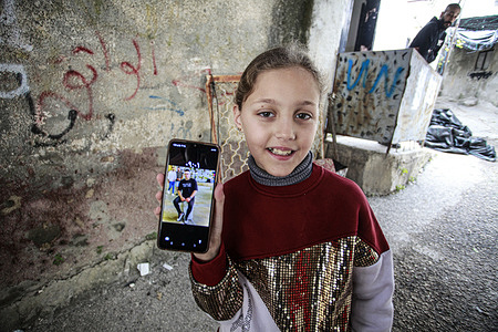 A Palestinian girl shows a picture of her brother, one of the three young men who were shot dead by Israeli forces last night during a raid on the Jenin refugee camp in the northern occupied West Bank.