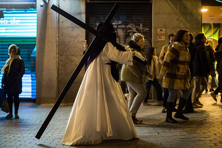 A penitent carrying a cross on his shoulder from the brotherhood of Nazarenes of Our Father Jesus of Health during the procession called The Gypsies through the streets of the center of Madrid. On the night of Holy Wednesday through the streets of Madrid, the image of Our Father Jesus of Health, from the church of El Carmen, came out in procession.