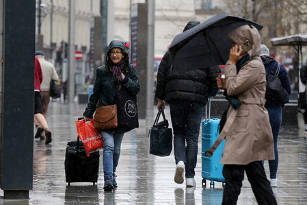 People walk on the street during the rainfall in central London.