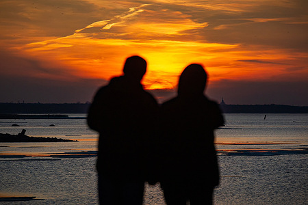 Silhouettes of a couple standing on Pearl Beach during sunset in St. Petersburg.