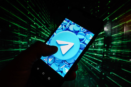 In this photo illustration, a Telegram logo is displayed on a smartphone with coding on the background.