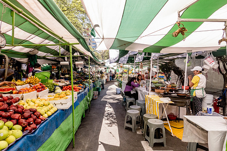 View of a food market in Condesa neighborhood in Mexico City. The street food market in Condesa, Mexico City, is a lively spot where you can find a variety of authentic Mexican dishes like tacos al pastor and elotes, perfect for experiencing the city's vibrant street food scene.