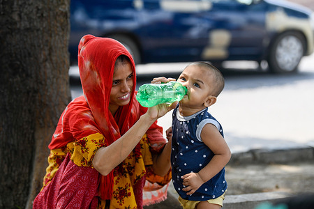 A mother gives water to her child during hot weather in Dhaka.