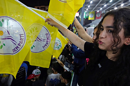 A young Kurdish girl is seen waving the flag of the People's Equality and Democracy Party at the celebration. The reappointment of Abdullah Zeydan, a member of the People's Equality and Democracy Party (DEM Parti), who won the Metropolitan Municipality Mayorship in Van but was initially denied an election certificate, sparked celebrations with a rally and concert held in Diyarbakir following events in Van. The Electoral Board's decision led to significant protests in the Kurdish region and in cities like Istanbul and Izmir.